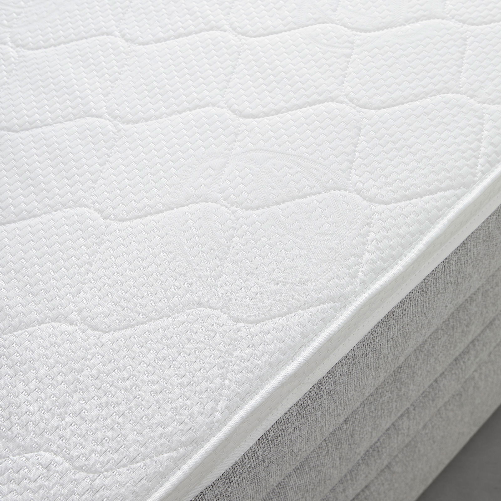 Nahaufnahme einer weißen Matratze auf einem Boxspringbett, seitliche Perspektive