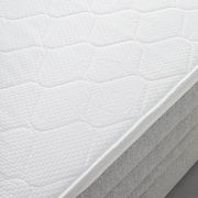 Nahaufnahme einer weißen Matratze auf einem Boxspringbett, seitliche Perspektive