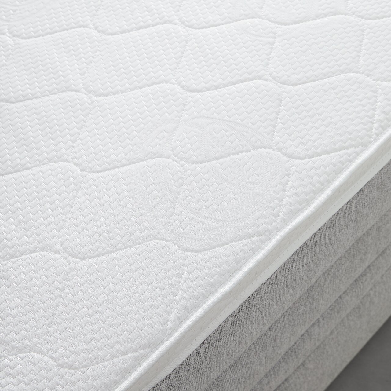 Nahaufnahme einer weißen Matratze auf einem Boxspringbett, seitliche Perspektive