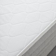 Nahaufnahme einer weißen Matratze auf einem Boxspringbett, seitliche Perspektive