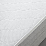 Nahaufnahme einer weißen Matratze auf einem Boxspringbett, seitliche Perspektive
