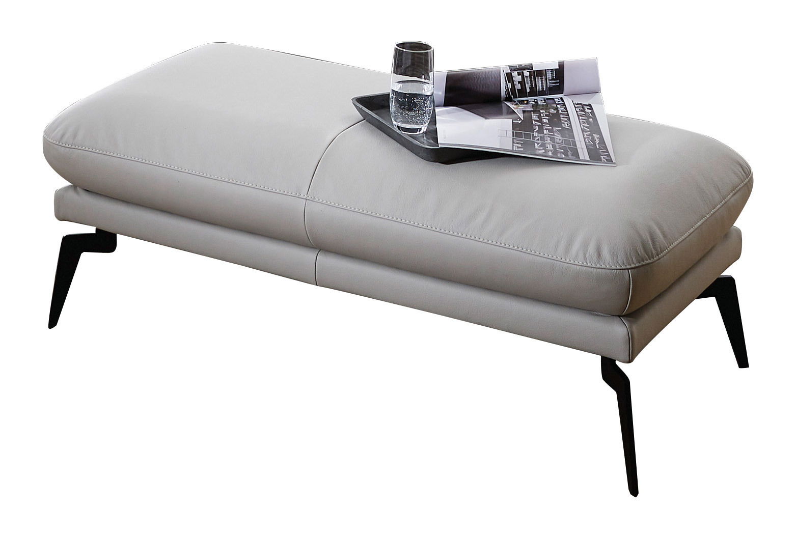 Graue Hockerbank mit schwarzem Metallgestell, darauf ein Tablett mit Glas und Zeitschrift, seitliche Perspektive.