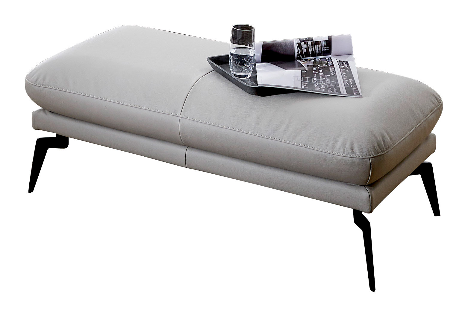Graue Hockerbank mit schwarzem Metallgestell, darauf ein Tablett mit Glas und Zeitschrift, seitliche Perspektive.