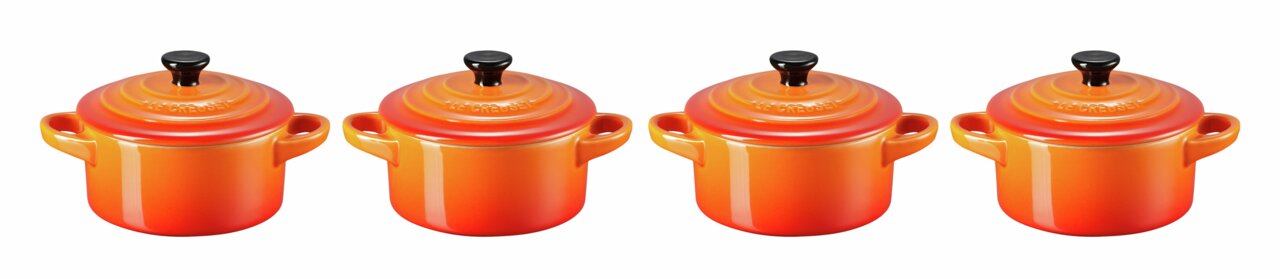 LE CREUSET Mini-Cocotte 4er-Set 10cm Ofenrot Vier Mini-Cocottes in leuchtendem Ofenrot, frontal nebeneinander aufgereiht, mit schwarzen Knöpfen auf den Deckeln.