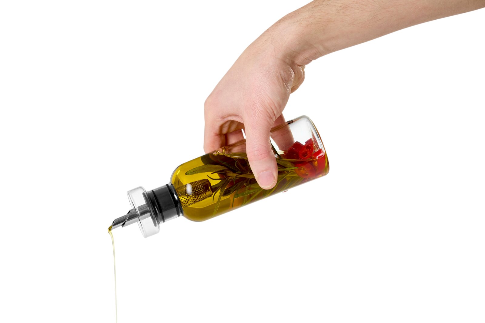 Hand hält eine transparente Ölflasche mit Ausgießer; Kräuter und rote Chiliringe im Öl, Öl wird ausgegossen, Seitenansicht in Nahaufnahme vor weißem Hintergrund