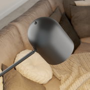 Moderne schwarze Stehleuchte mit abgerundetem Lampenschirm, von oben betrachtet, über einem gemütlichen Sofa mit Kissen.