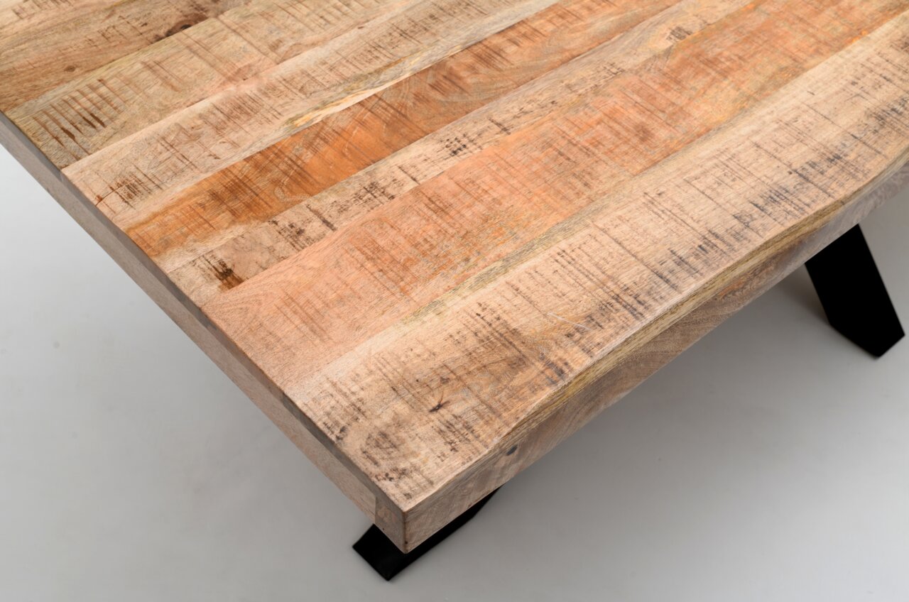 Nahaufnahme eines Esstisches aus Holz mit natürlicher Maserung und stabilen schwarzen Metallbeinen, aus der Vogelperspektive fotografiert.