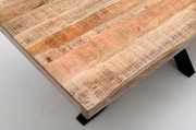 Nahaufnahme eines Esstisches aus Holz mit natürlicher Maserung und stabilen schwarzen Metallbeinen, aus der Vogelperspektive fotografiert.