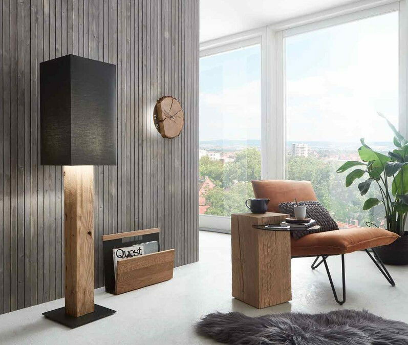 Moderne Wanduhr aus Holz an einer vertäfelten Wand, seitliche Perspektive.