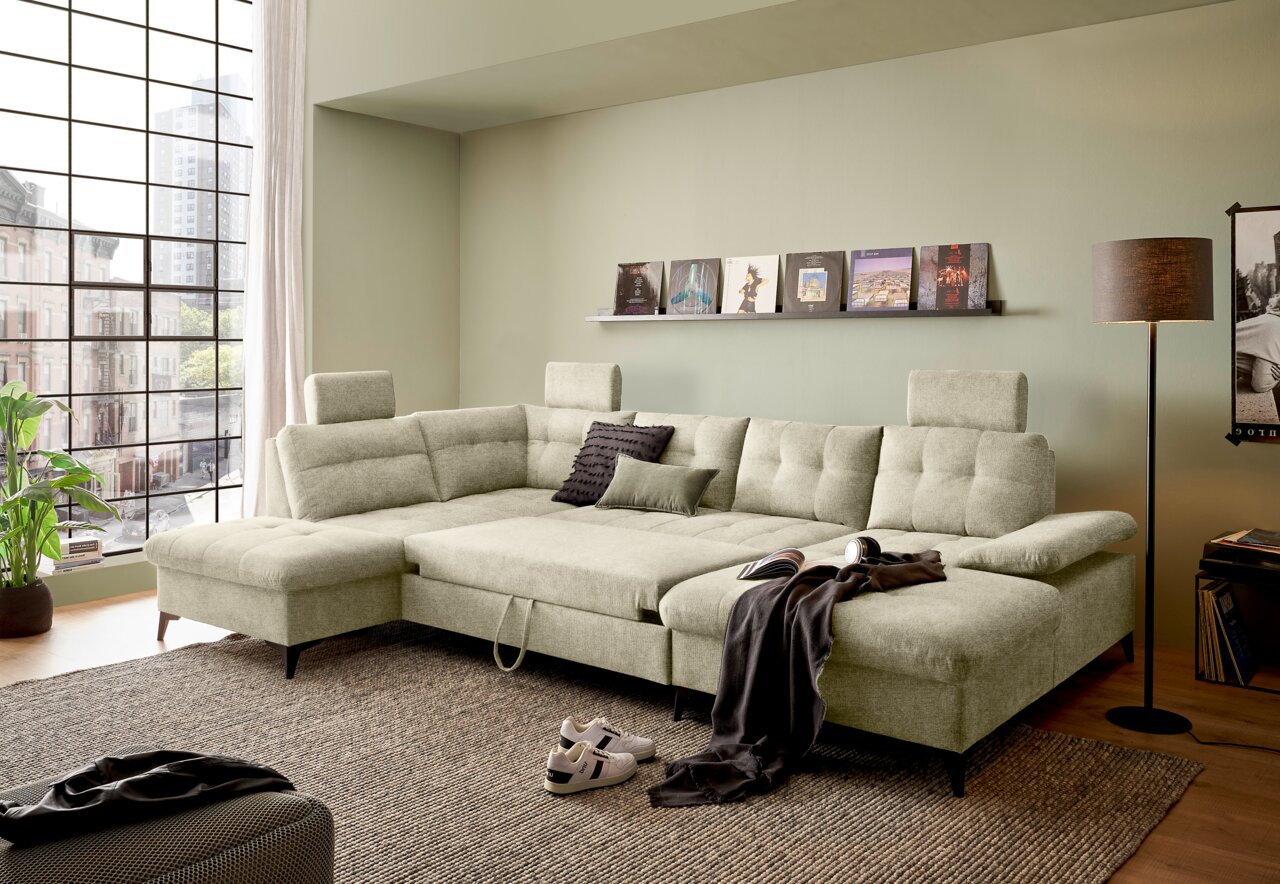 Großes, modernes U-förmiges Sofa in einem hellen Wohnzimmer mit großen Fenstern, seitliche Perspektive.