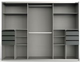 Innenansicht eines dreitürigen Schwebetürenschranks mit mehreren Regalböden, Schubladen und einer Kleiderstange, frontal betrachtet.