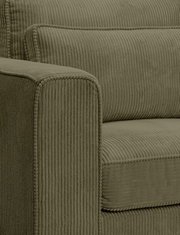 Nahaufnahme eines olivgrünen Cord-Sofas mit geripptem Bezug, sichtbarer Armlehne und Sitz-/Rückenkissen, fotografiert aus schräger Seitenperspektive