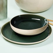 Dunkelgrünes Tafelset bestehend aus einem flachen Teller und einer Schale, seitliche Perspektive.