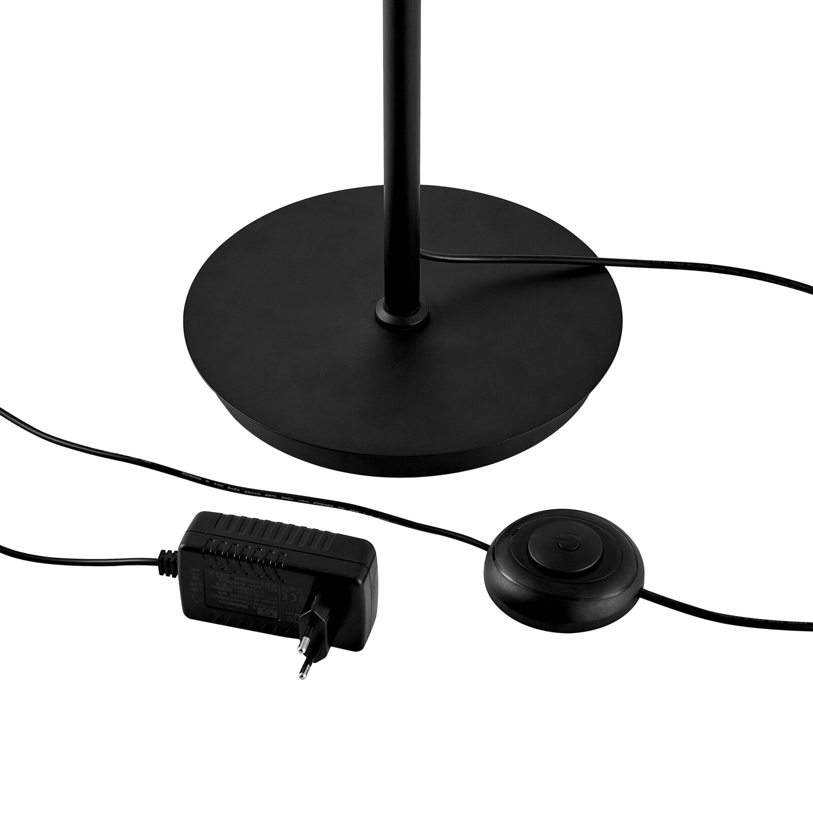 Runder schwarzer Lampenfuß einer Stehleuchte mit Kabel, Fußschalter und Netzteil, Detailansicht aus leicht schräger Seitenperspektive von oben