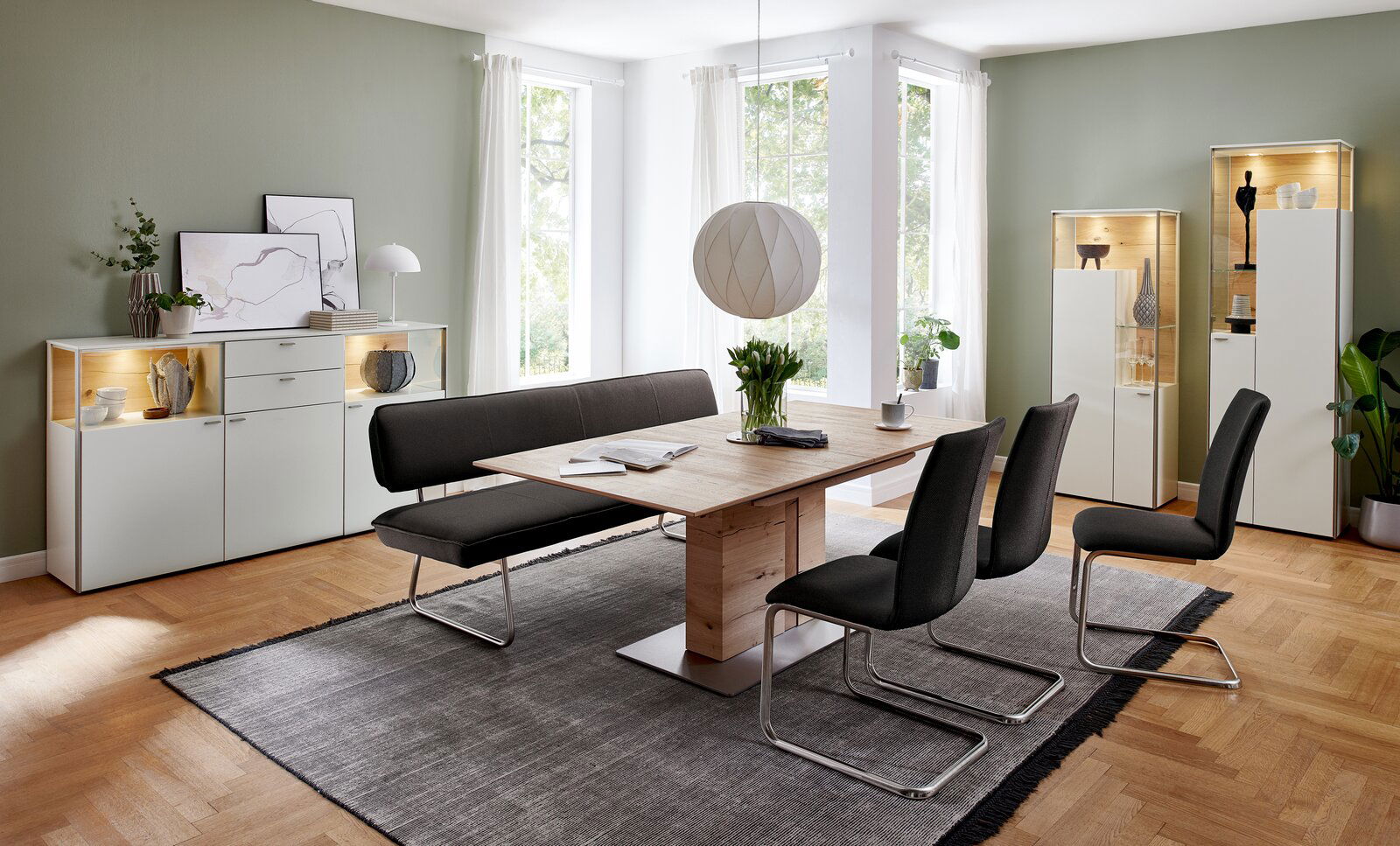 Moderner Esstisch aus Holz mit schwarzer Sitzbank und Stühlen in einem hellen Esszimmer, seitliche Perspektive