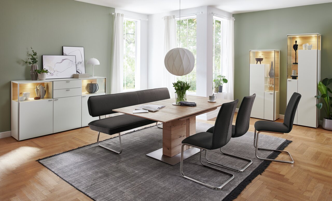 Moderner Esstisch aus Holz mit schwarzer Sitzbank und Stühlen in einem hellen Esszimmer, seitliche Perspektive