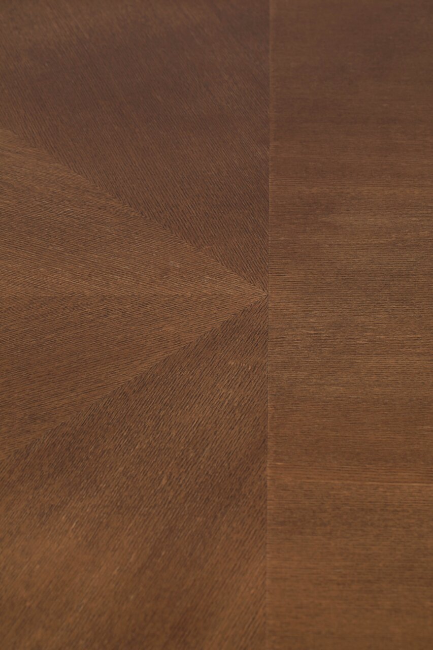 Nahaufnahme der Holzmaserung eines Esstisches aus dunklem Holz, von oben betrachtet.