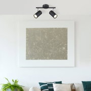 Zwarte plafondspot met twee lampen in een moderne woonkamer, gezien van onderaf.