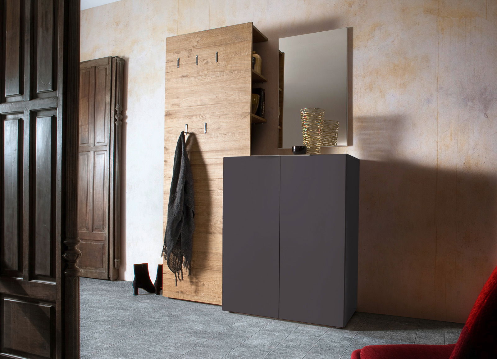Moderner Eingangsbereich mit einem Schuhschrank in dunklem Design, einem Garderobenpaneel aus Holz mit Haken und einem Spiegel. Perspektive von der Seite.
