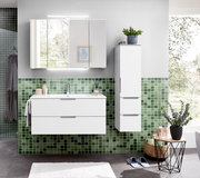 Modernes weißes Badmöbel-Set mit Waschtisch-Unterschrank, hohem Seitenschrank und Spiegelschrank mit LED-Beleuchtung vor grüner Mosaikfliesenwand, Frontalansicht.