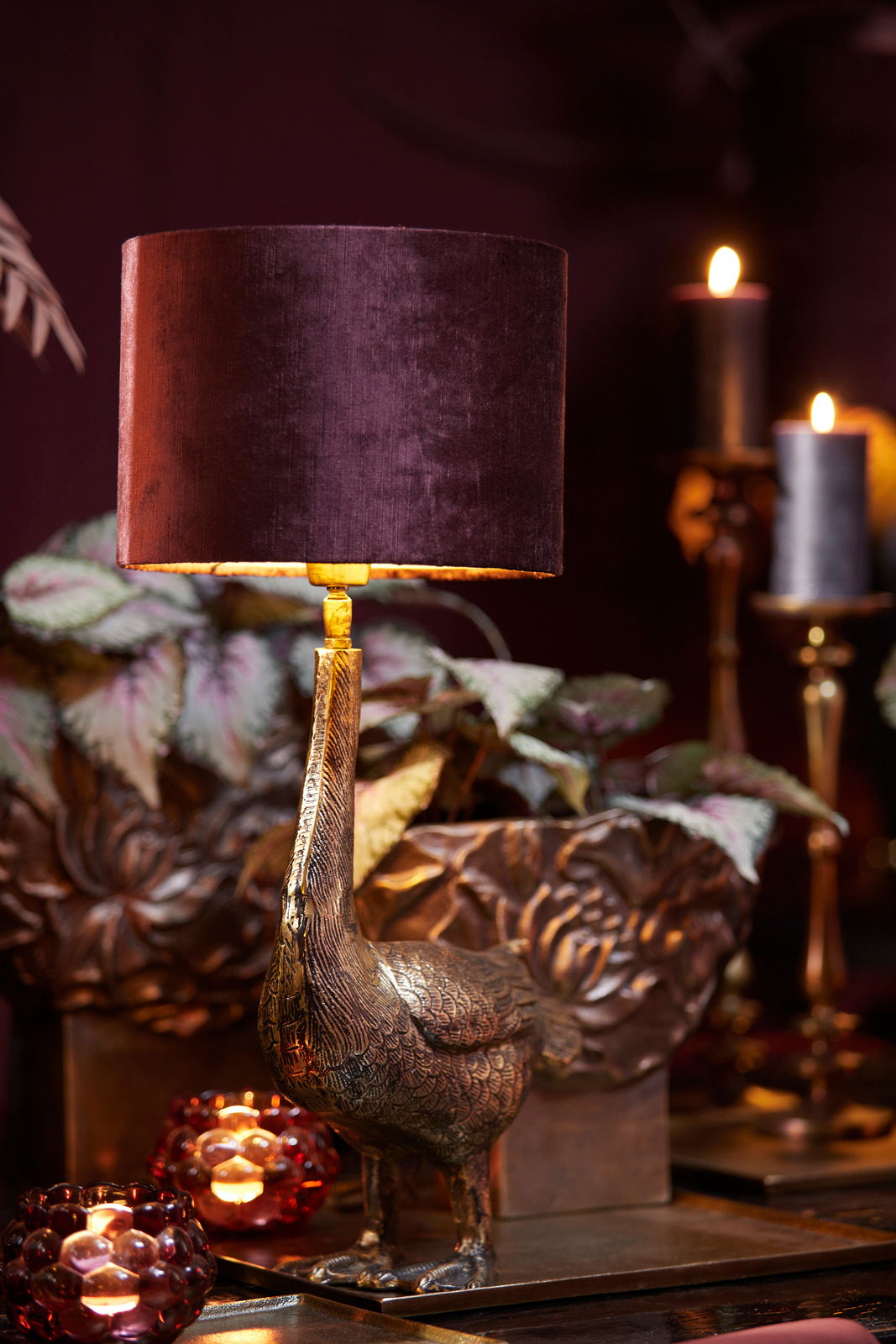 Eleganter Lampenschirm in dunklem Samt, getragen von einer goldenen Vogelstatue, seitliche Perspektive.