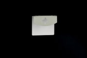 Weiße, rechteckige Verpackungskarte mit grauem Aufhänger/Lasche und Kleeblatt-förmiger Stanzung, frontal von oben auf schwarzem Hintergrund fotografiert