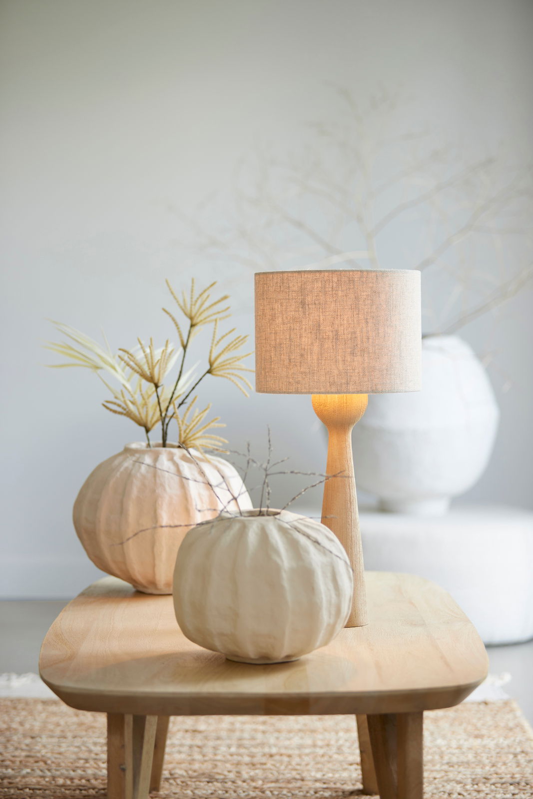 Light&Living Lampenschirm Zylindrischer Lampenschirm in natürlichem Beige auf einem Holztisch, umgeben von dekorativen Elementen. Frontalansicht.