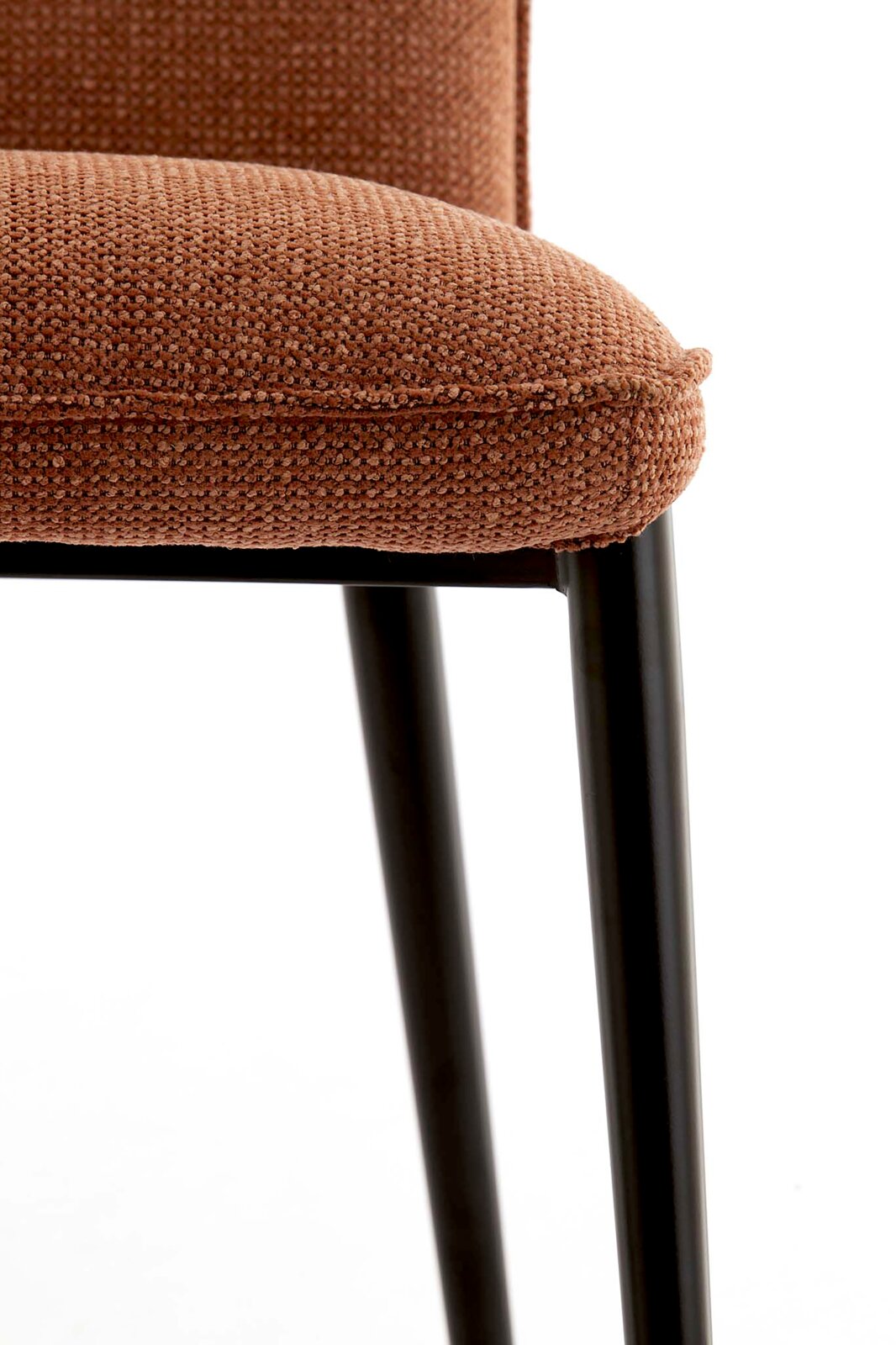 Detailfoto van een gestoffeerde stoel met een bruine, gestructureerde stoffen bekleding en zwarte metalen poten; close-up van de zitrand en de poten aan de zijkant