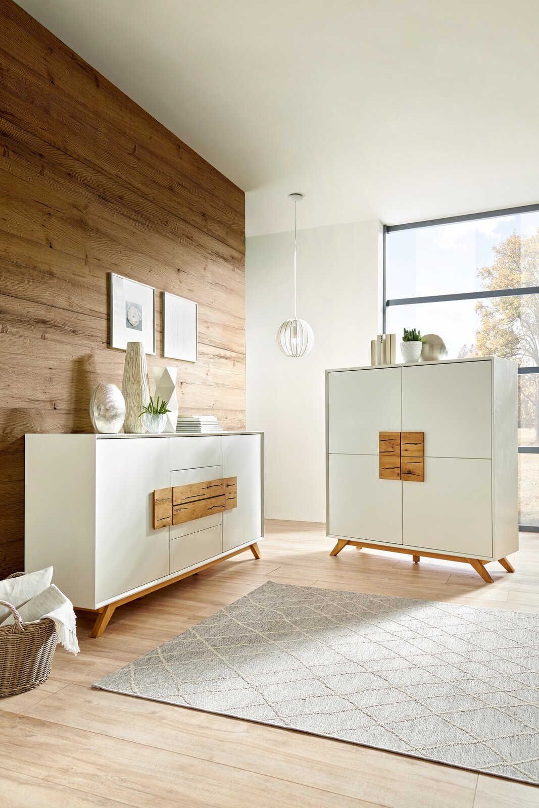 Modernes Highboard und Sideboard in einem hellen Raum mit Holzwand und großen Fenstern, seitliche Perspektive.