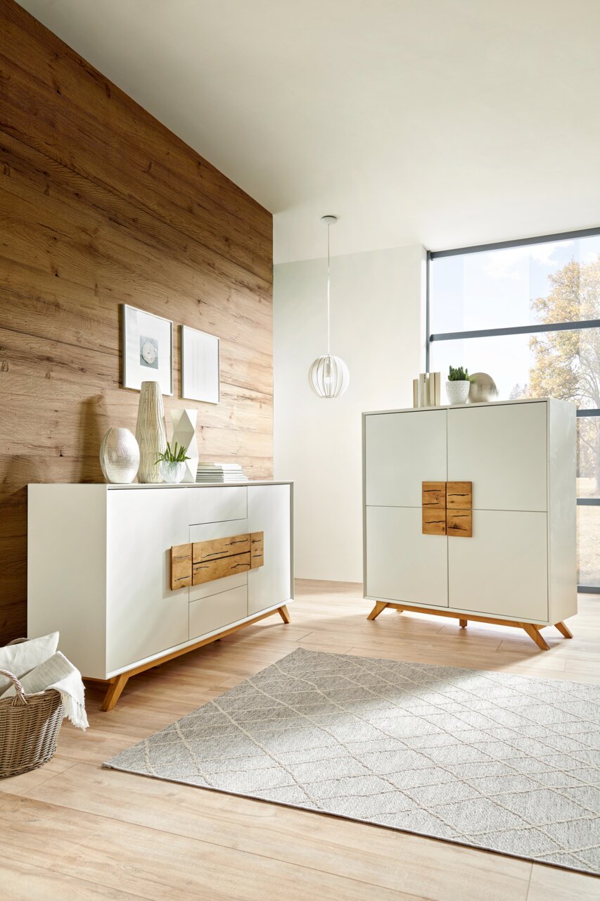 Een modern hoogkast en dressoir in een lichte ruimte met een houten wand en grote ramen, gezien vanuit de zijkant.