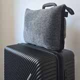 Graue Reisedecke in einer Tasche auf einem schwarzen Koffer, seitliche Perspektive