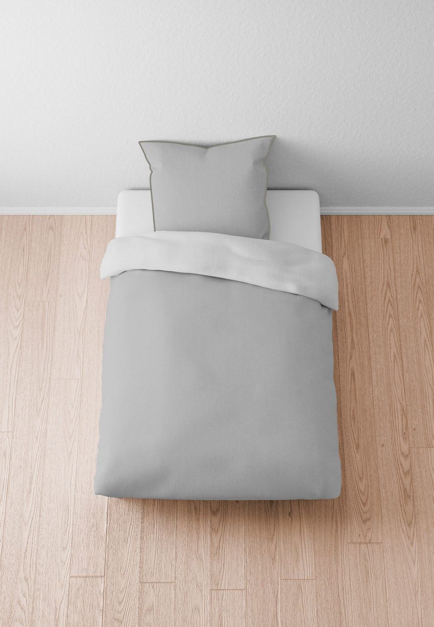 Graue Bettwäsche 155x220cm auf einem Bett, von oben fotografiert, auf hellem Holzboden.