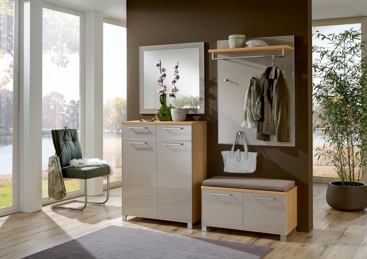 Moderne Garderobeneinrichtung mit Spiegel, Schuhschrank und Garderobenpaneel in einem hellen Raum mit Blick auf den Garten. Frontalansicht.
