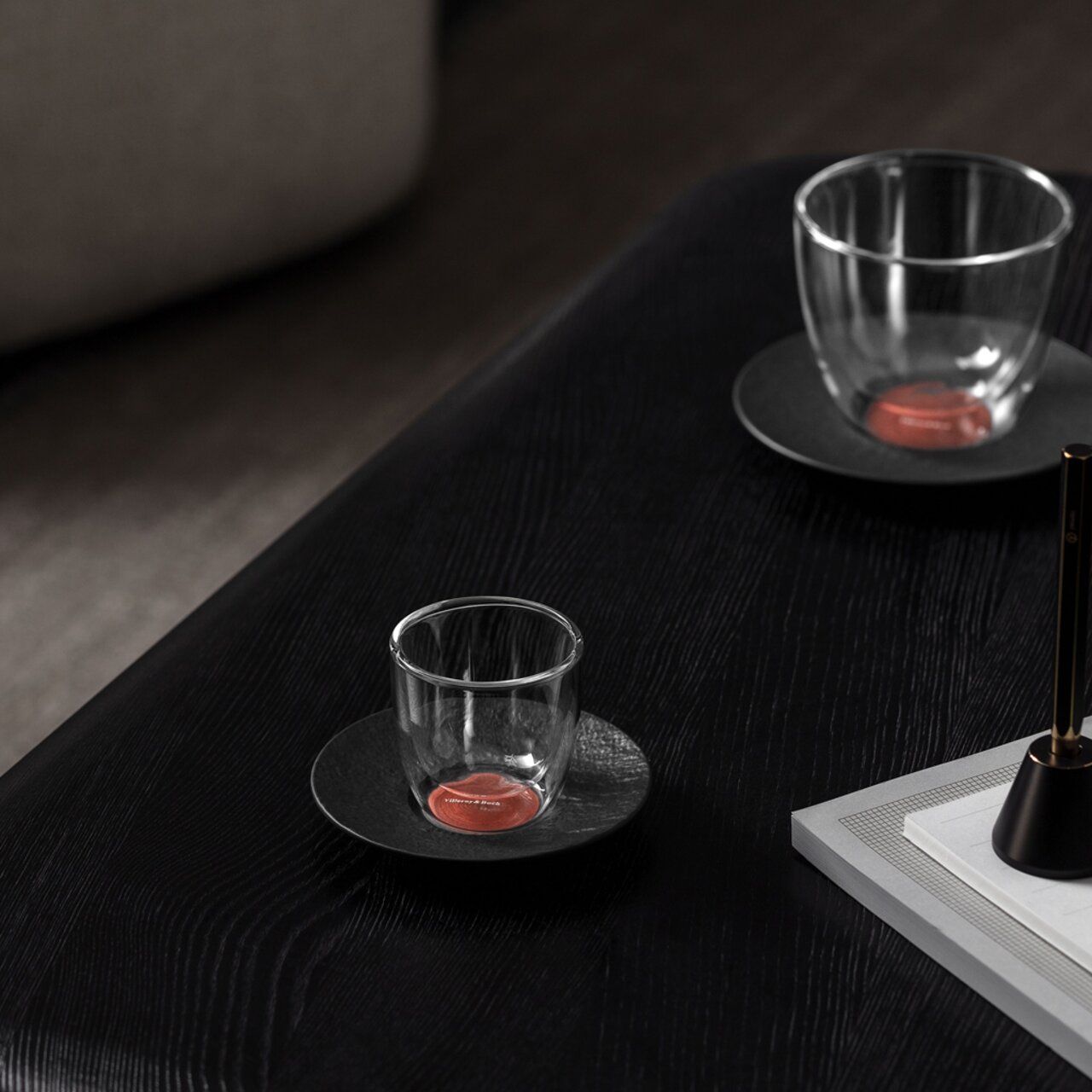 Zwei Espressountertassen aus der Manufacture-Serie mit transparenten Gläsern, auf einem dunklen Holztisch von oben betrachtet.