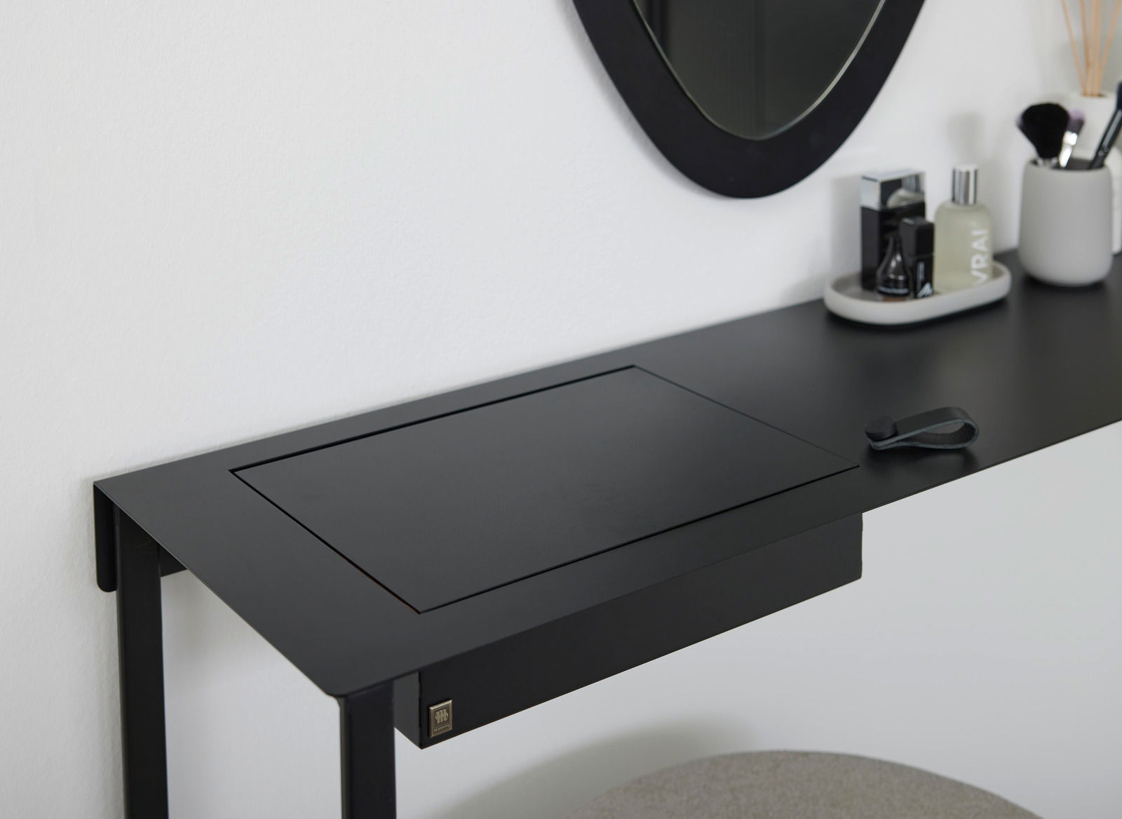 Schwarzer Konsolentisch oder Schreibtisch aus Metall mit integriertem Fach, seitliche Perspektive, dekoriert mit Spiegel und Accessoires.