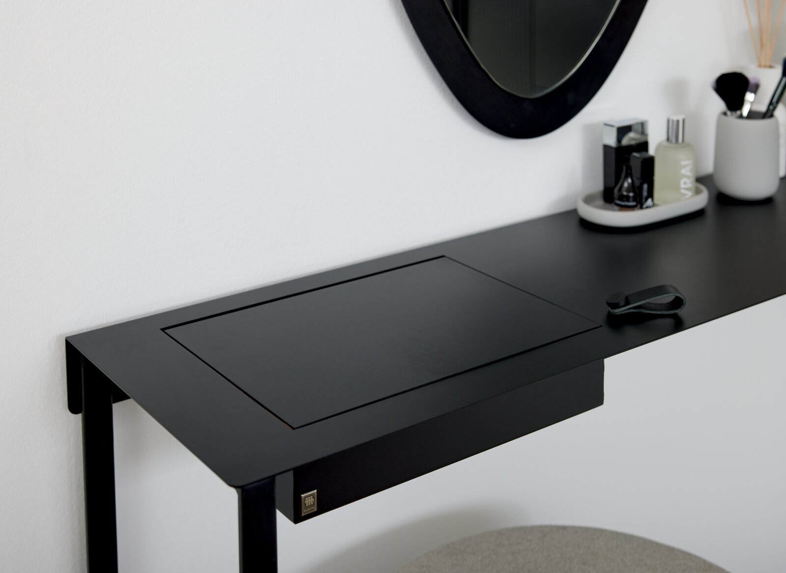 Schwarzer Konsolentisch oder Schreibtisch aus Metall mit integriertem Fach, seitliche Perspektive, dekoriert mit Spiegel und Accessoires.