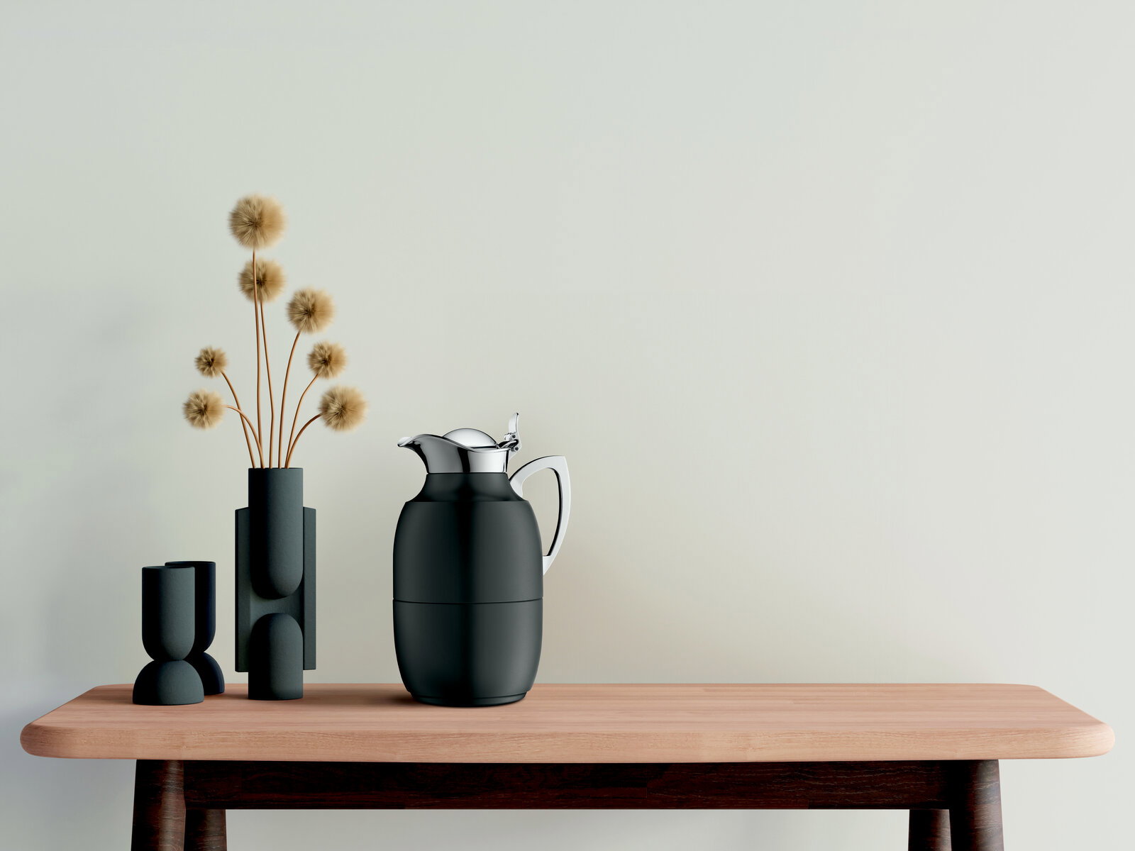 Isolierkanne Juwel in mattem Schwarz mit glänzendem Deckel, auf einem Holztisch neben modernen Vasen, seitliche Perspektive