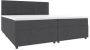 Dunkelgraues Boxspringbett mit gepolstertem, quadratisch gestepptem Kopfteil und weißer Matratzenauflage, in frontaler leicht seitlicher Ansicht