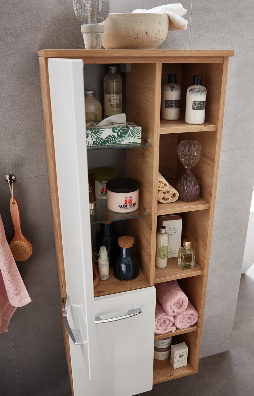 Moderne houten midikast met open planken en een witte deur, gevuld met verzorgingsproducten en handdoeken, gefotografeerd vanuit een schuin bovenaanzicht.