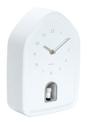 Weiße Wanduhr in Hausform mit minimalistischen Ziffern und einer kleinen Katzenfigur in einer Öffnung unten, seitliche Perspektive.