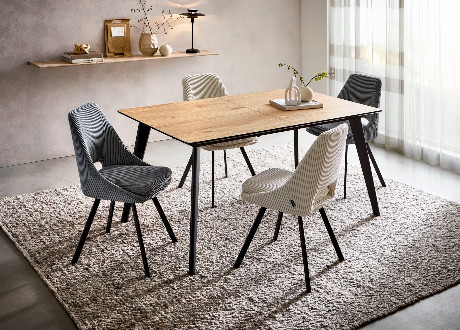 Z2 Funktions-Esstisch MARKOS Moderner Esstisch mit Holzplatte und schwarzen Metallbeinen, umgeben von vier gepolsterten Stühlen in verschiedenen Farben, aus seitlicher Perspektive fotografiert.