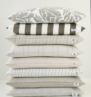 Stapel von Outdoor-Kissen in verschiedenen Mustern und neutralen Farben, seitliche Perspektive