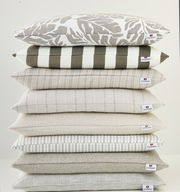 Stapel von Outdoor-Kissen in verschiedenen Mustern und neutralen Farben, seitliche Perspektive