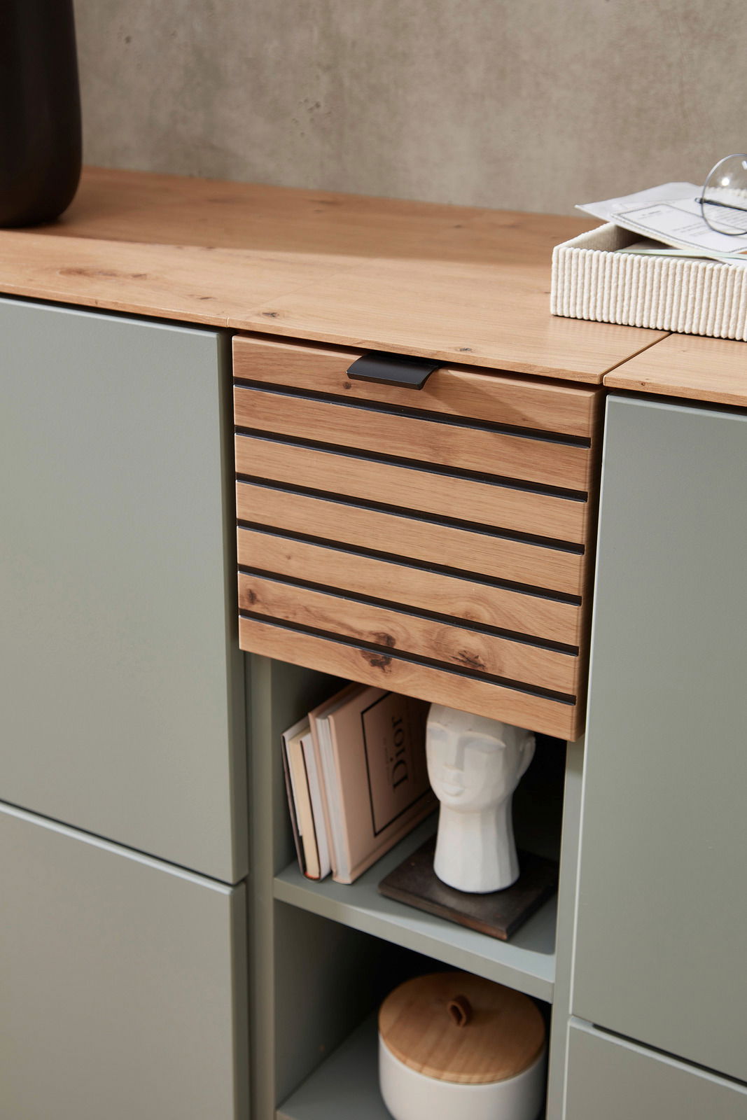 Detailansicht eines modernen Garderoben-Sets mit Holz- und Metallelementen, dekoriert mit Büchern und einer Skulptur.