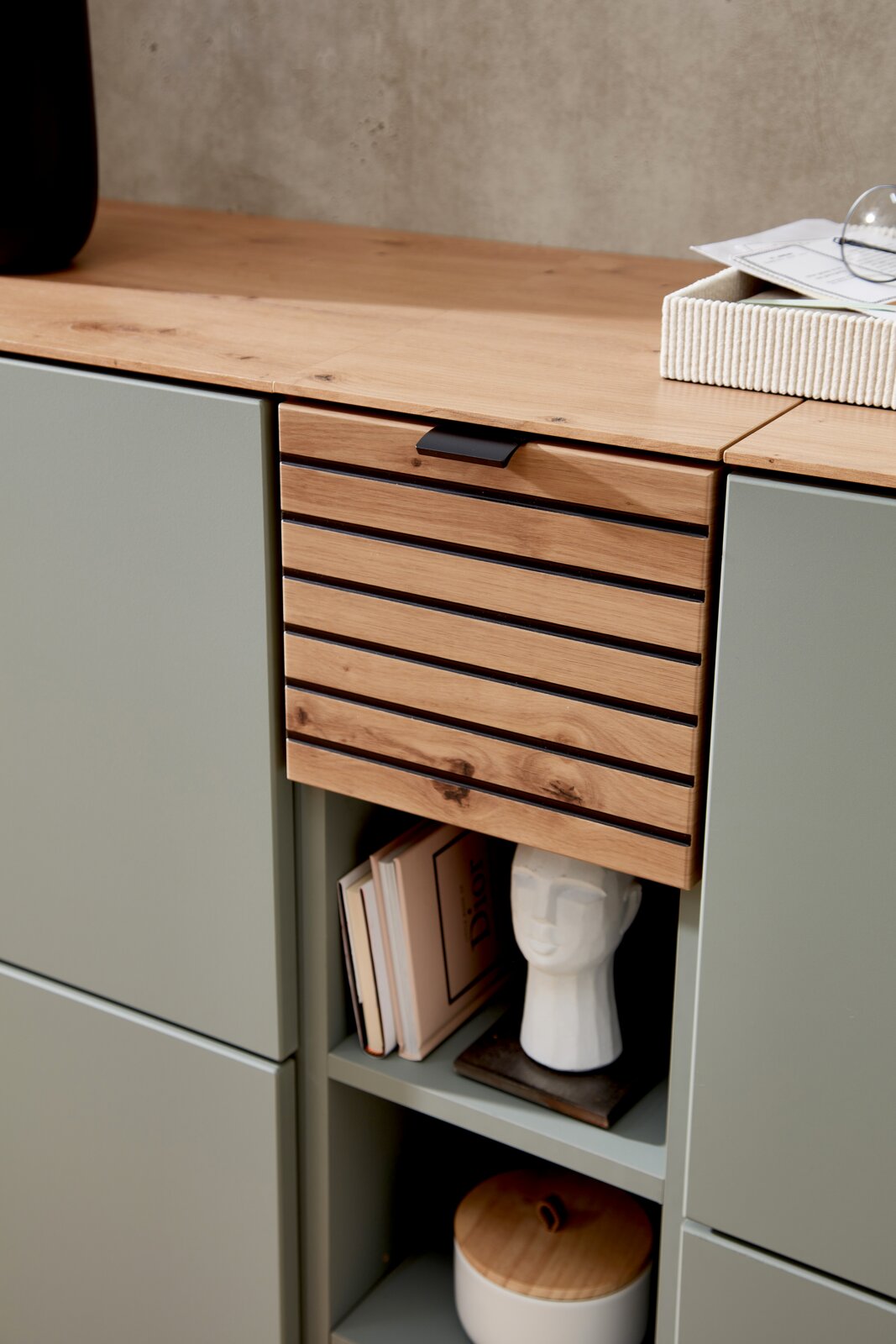Detailansicht eines modernen Garderoben-Sets mit Holz- und Metallelementen, dekoriert mit Büchern und einer Skulptur.