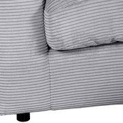 Nahaufnahme einer grauen, gerippten Stoffoberfläche eines Sofas mit schwarzem Bein, perspektivisch von der Seite.