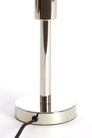 Nahaufnahme eines glänzenden, metallischen Lampenfußes mit rundem Sockel und Stromkabel, seitliche Perspektive