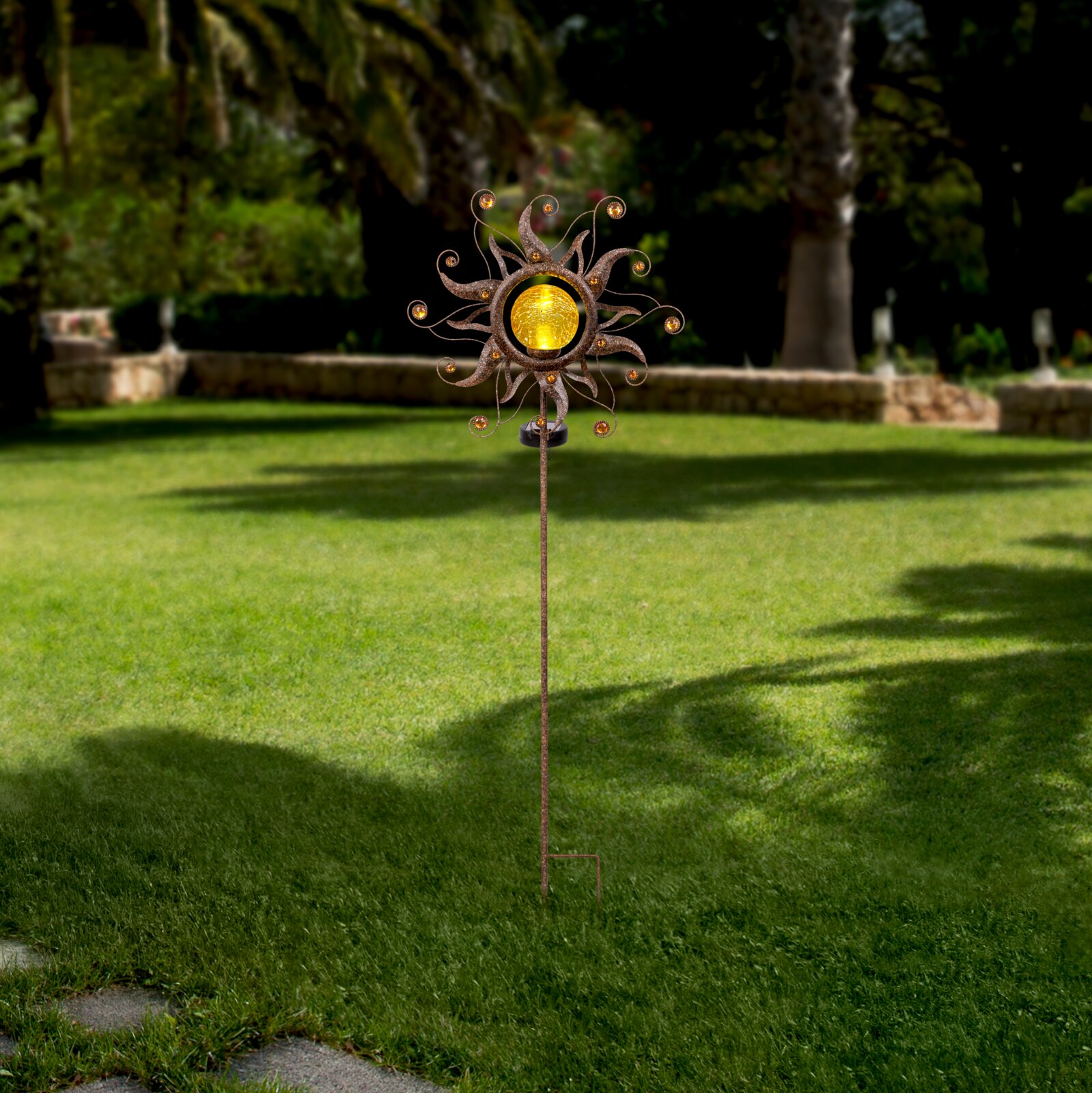 Ambia Garden Solarleuchte SOLARLEUCHTE Solarleuchte in Form einer Sonne mit dekorativen Elementen, aufgestellt in einem Garten, seitliche Perspektive