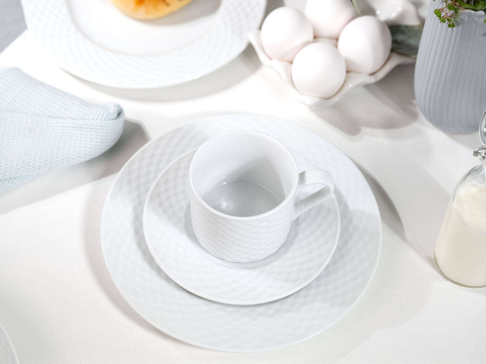 Kaffeeservice in eleganter weißer Optik mit Tasse, Untertasse und Teller, von oben fotografiert.