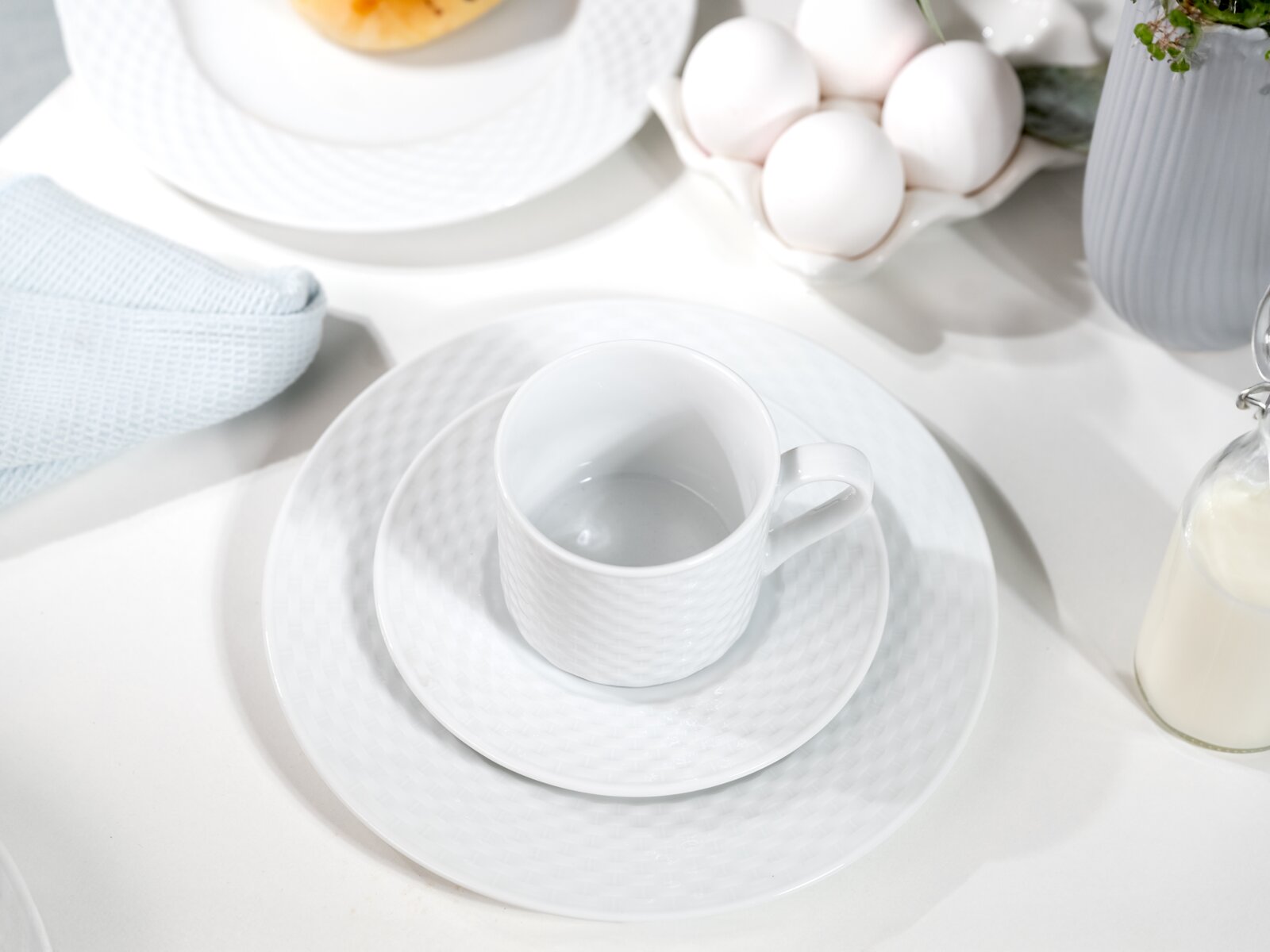 Kaffeeservice in eleganter weißer Optik mit Tasse, Untertasse und Teller, von oben fotografiert.